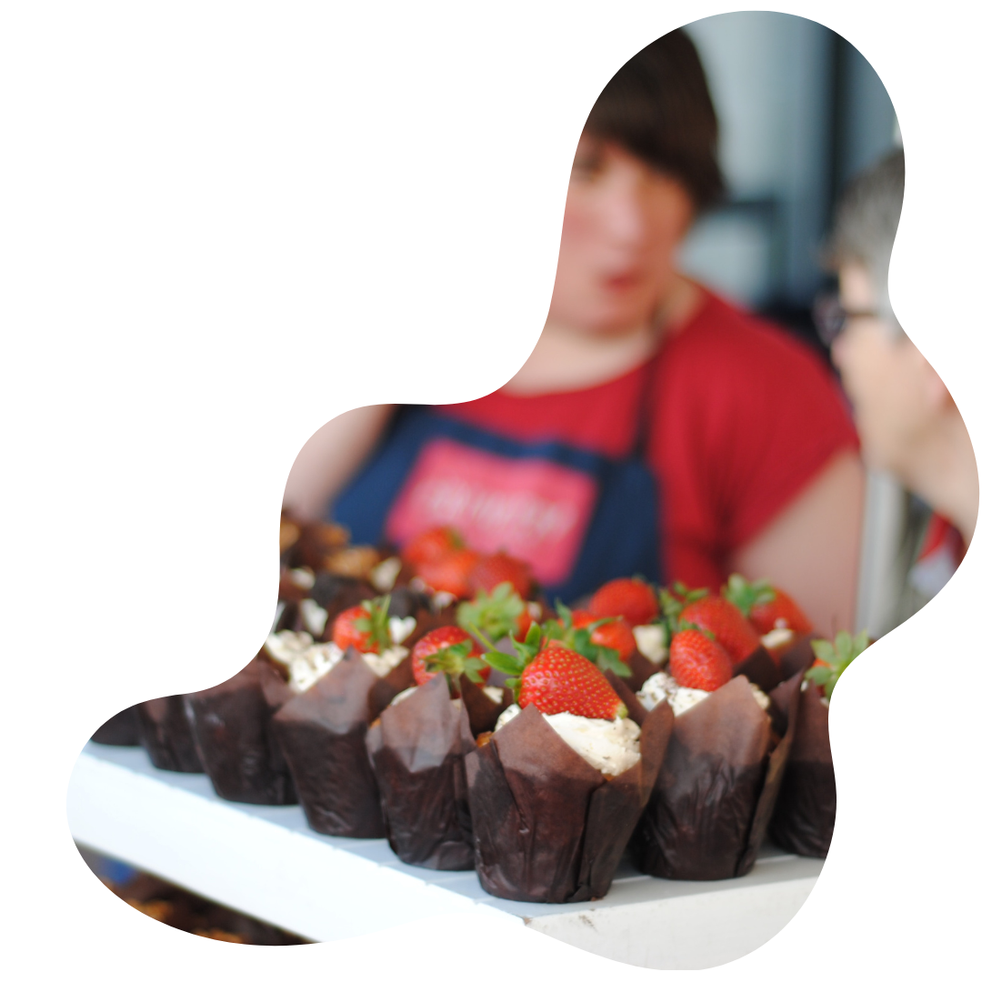 Lady with a chocolatte cupcake stall. Brown cased cupcakes with strawberry and cream on top