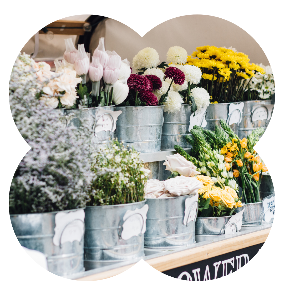 Variety of flowers displayed in galvanised buckets on a market stall 