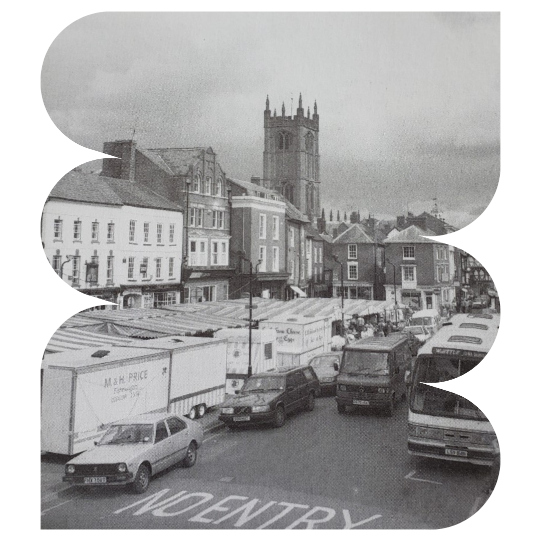 B&W image of Ludlow market with striped canopies and parked cars