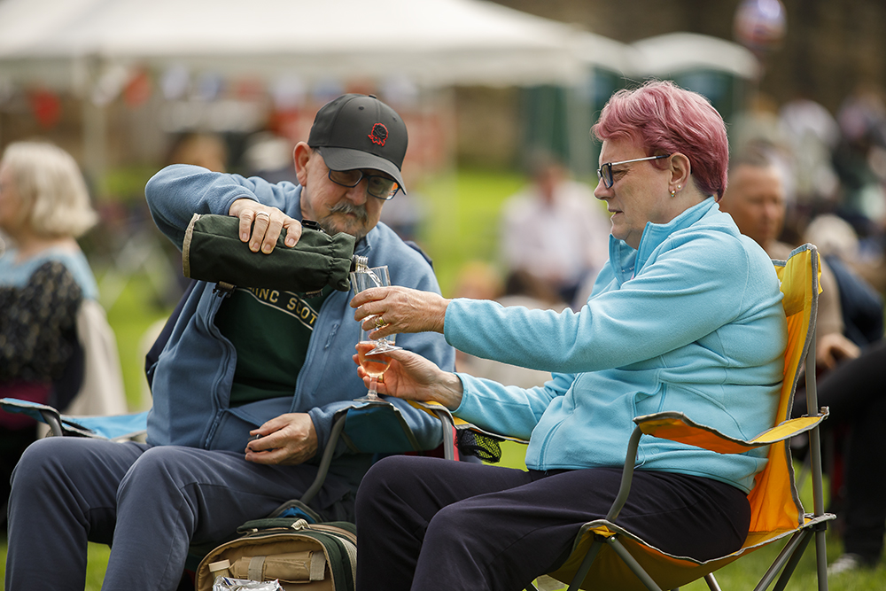 A couple enjoying a glass of wine sat on camping chairs for the big lunch celebrations.