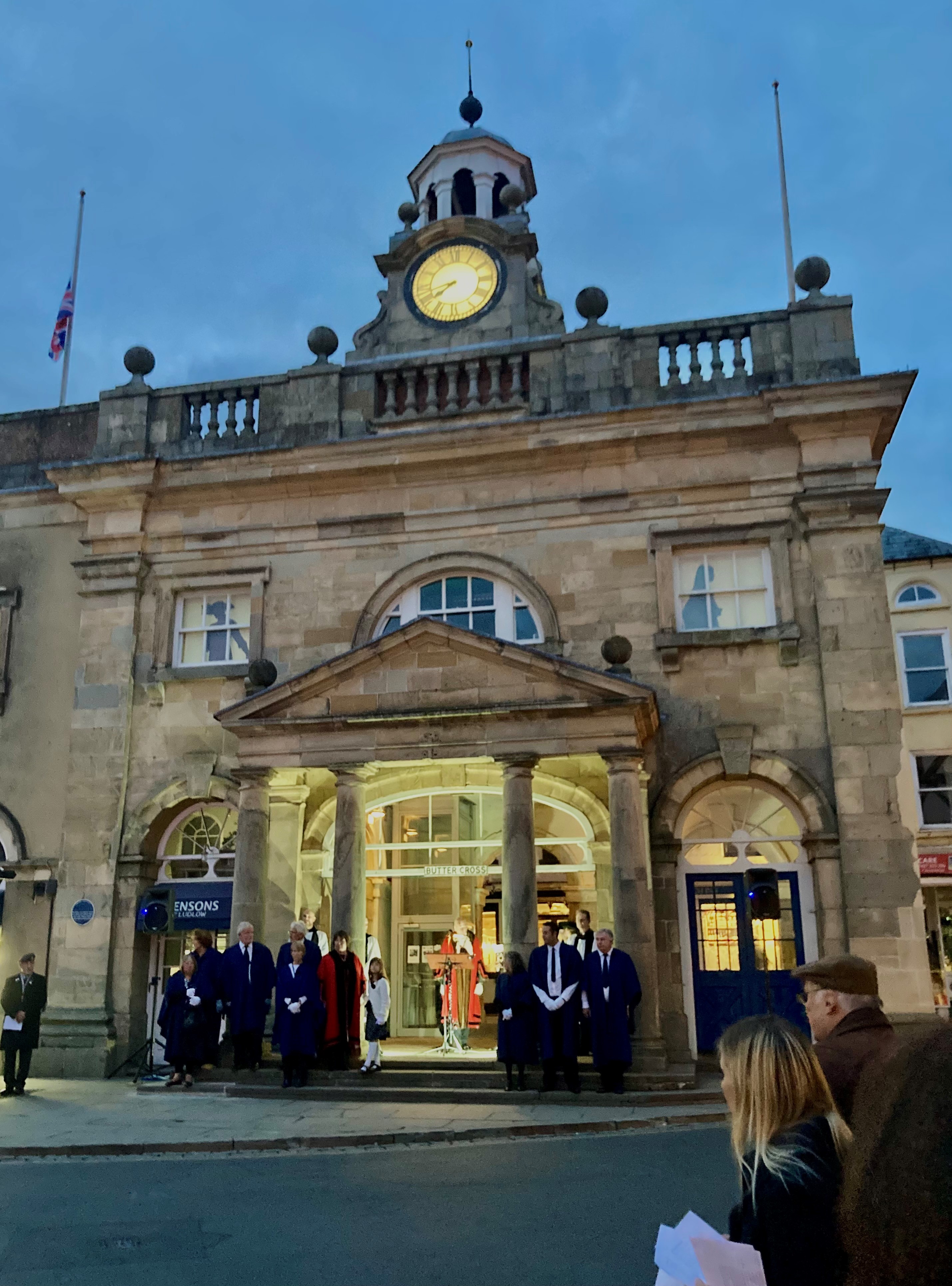 A crowd of onlookers watches the mayor lead them in a minutes silence